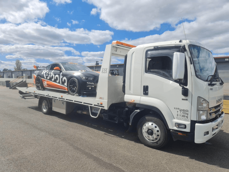 tow truck loaded with Kubota sports car
