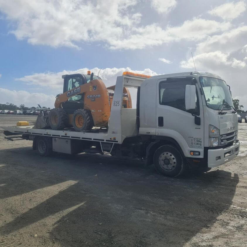 white tow truck loaded with excavator