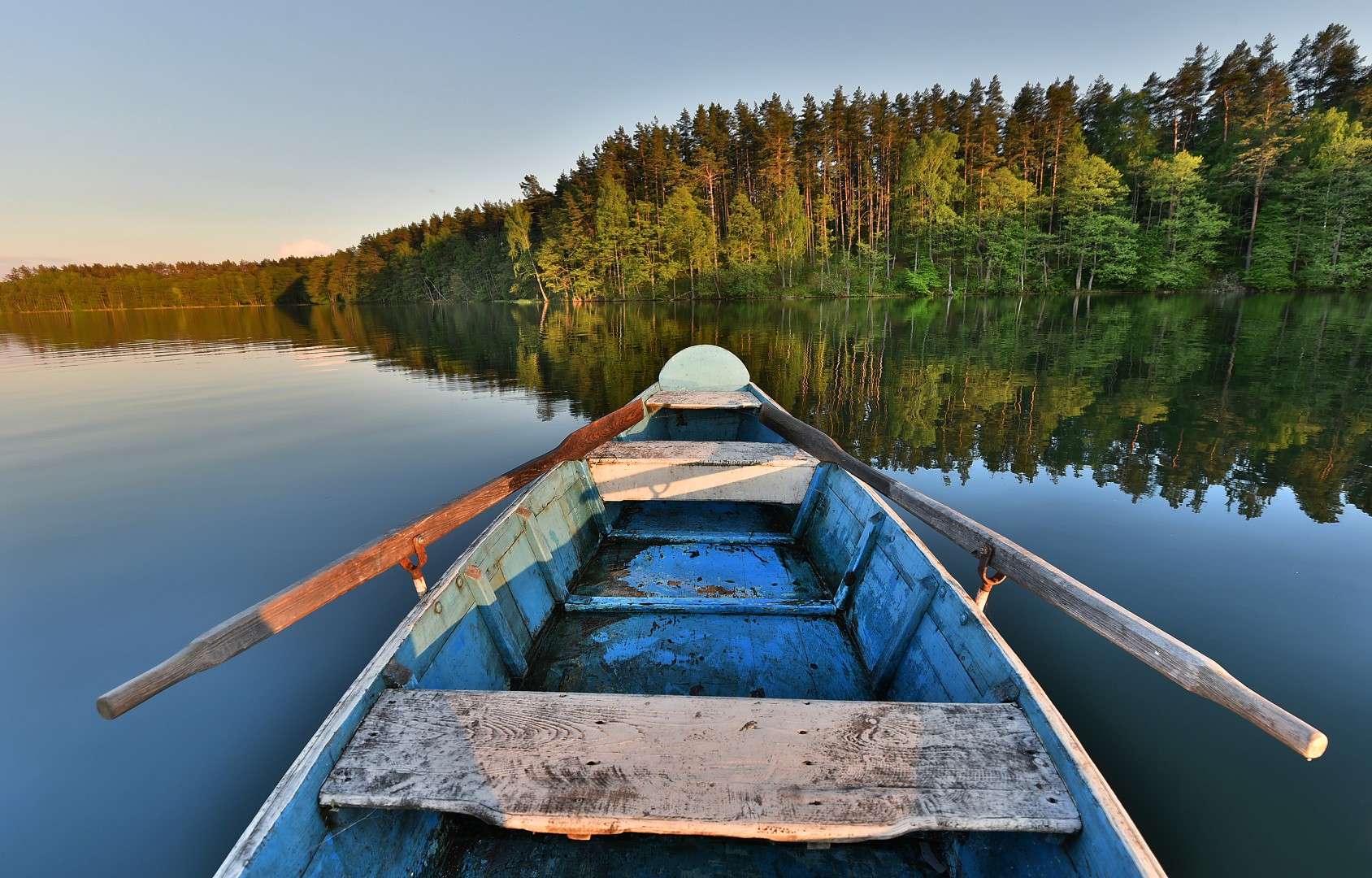 stock-photo-fishing-boat-in-a-calm-lake-water-old-wooden-fishing-boat-wooden-fishing-boat-in-a-still-lake-water-602188286