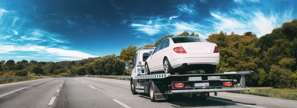Image of a white car on a flatbed truck after Accident towing
